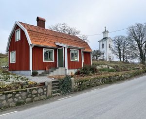 Ett rött litet hus med en köksträdgård i vintervila.